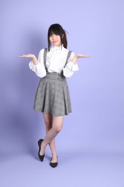 Mor arka planda duran beyaz giysili tatlı Asyalı kız.