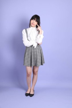 Mor arka planda duran beyaz giysili tatlı Asyalı kız.