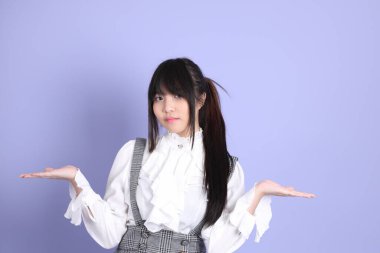 Mor arka planda duran beyaz giysili tatlı Asyalı kız.