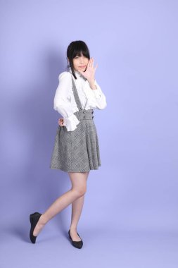 Mor arka planda duran beyaz giysili tatlı Asyalı kız.