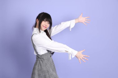 Mor arka planda duran beyaz giysili tatlı Asyalı kız.