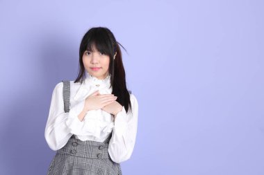 Mor arka planda duran beyaz giysili tatlı Asyalı kız.