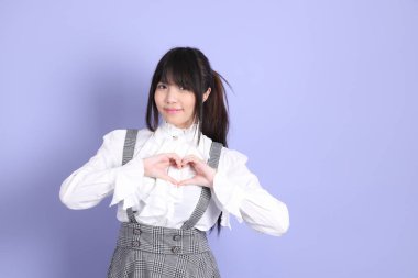 Mor arka planda duran beyaz giysili tatlı Asyalı kız.