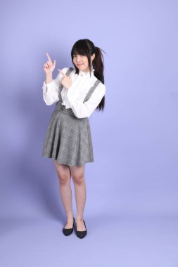 Mor arka planda duran beyaz giysili tatlı Asyalı kız.