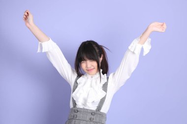 Mor arka planda duran beyaz giysili tatlı Asyalı kız.