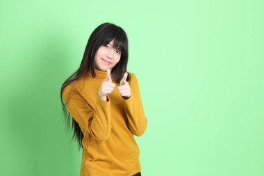 Yeşil arka planda sıradan giyinmiş, tatlı Asyalı genç kız.