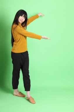 Yeşil arka planda sıradan giyinmiş, tatlı Asyalı genç kız.