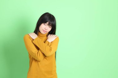 Yeşil arka planda sıradan giyinmiş, tatlı Asyalı genç kız.