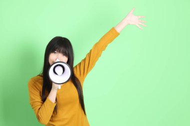 Yeşil arka planda sıradan giyinmiş, tatlı Asyalı genç kız.