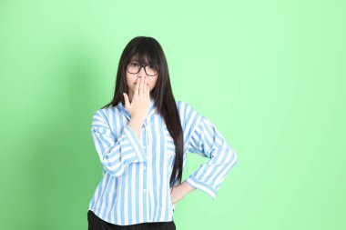 Yeşil arka planda sıradan giyinmiş genç Asyalı kız..