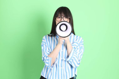 Yeşil arka planda sıradan giyinmiş, tatlı Asyalı genç kız.