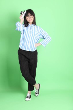 Yeşil arka planda sıradan giyinmiş, tatlı Asyalı genç kız.