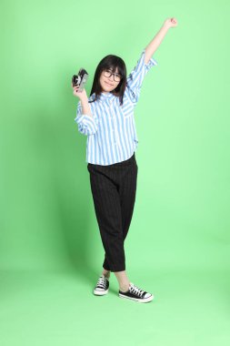 Yeşil arka planda sıradan giyinmiş, tatlı Asyalı genç kız.