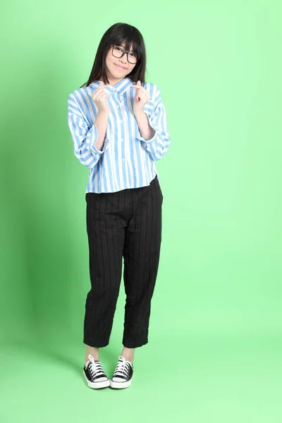 若いですアジアの女の子でカジュアル服を着た緑の背景に立って — ストック写真
