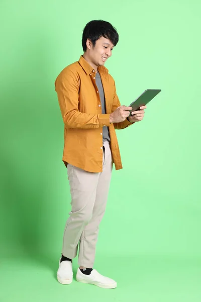 年轻的亚洲男子穿着漂亮的休闲装 站在浅绿色的背景上 — 图库照片