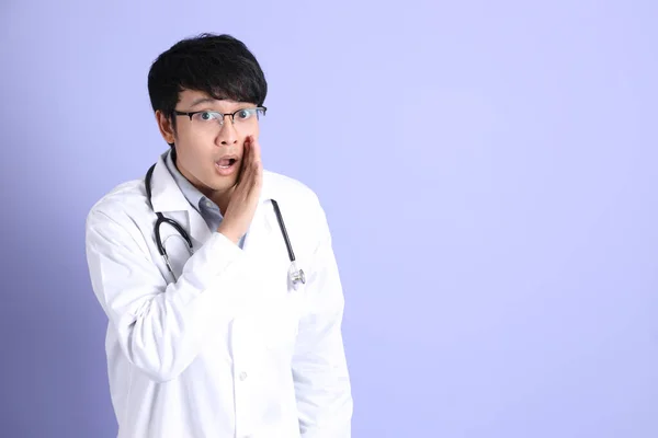 Νεαρός Ενήλικος Ασιάτης Γιατρός Στέκεται Στο Μωβ Φόντο — Φωτογραφία Αρχείου