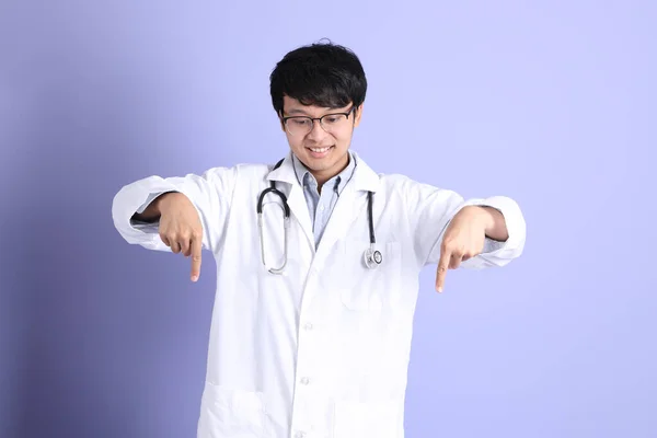 站在紫色背景上的年轻的亚洲医生 — 图库照片