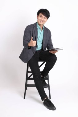 Genç yetişkin iş adamı beyaz arka planda oturuyor..