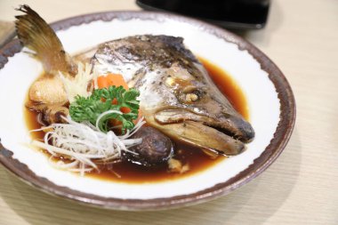 Soya çorbasında kaynatılmış somon balığı kafası mantar ve havuçla servis edilir..