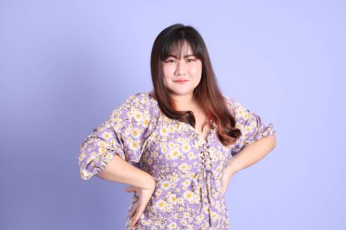 Mor arka planda sıradan kıyafetlerle duran tombul Asyalı kadın..