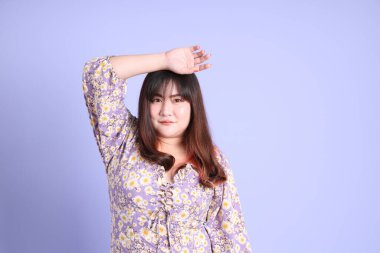 Mor arka planda sıradan kıyafetlerle duran tombul Asyalı kadın..