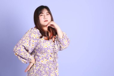 Mor arka planda sıradan kıyafetlerle duran tombul Asyalı kadın..