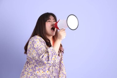 Mor arka planda sıradan kıyafetlerle duran tombul Asyalı kadın..