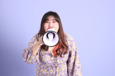 Mor arka planda sıradan kıyafetlerle duran tombul Asyalı kadın..