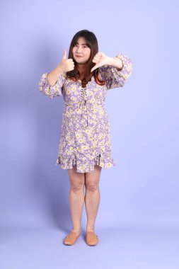 Mor arka planda sıradan kıyafetlerle duran tombul Asyalı kadın..