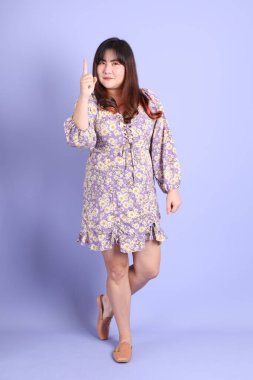 Mor arka planda sıradan kıyafetlerle duran tombul Asyalı kadın..