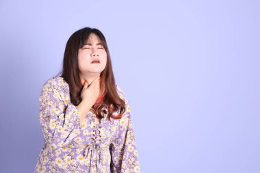 Mor arka planda sıradan kıyafetlerle duran tombul Asyalı kadın..