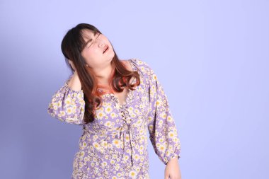 Mor arka planda sıradan kıyafetlerle duran tombul Asyalı kadın..