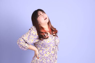 Mor arka planda sıradan kıyafetlerle duran tombul Asyalı kadın..