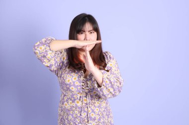 Mor arka planda sıradan kıyafetlerle duran tombul Asyalı kadın..