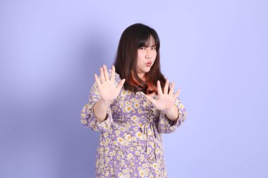 Mor arka planda sıradan kıyafetlerle duran tombul Asyalı kadın..