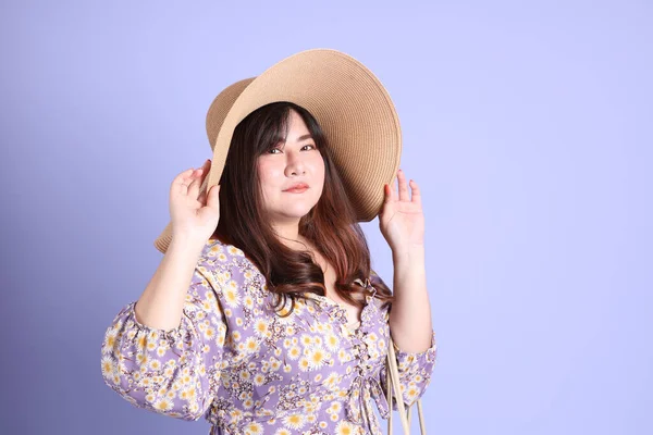 Mor arka planda sıradan kıyafetlerle duran tombul Asyalı kadın..