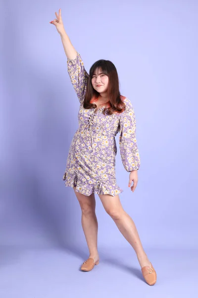 那个穿着休闲装站在紫色背景上的胖胖的亚洲女人 — 图库照片