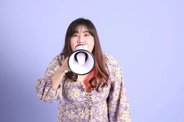 Mor arka planda sıradan kıyafetlerle duran tombul Asyalı kadın..