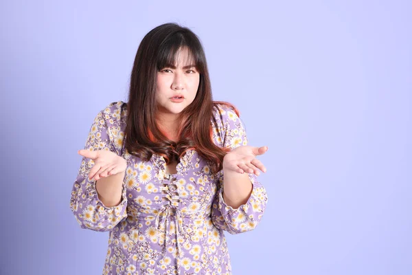 Mor arka planda sıradan kıyafetlerle duran tombul Asyalı kadın..