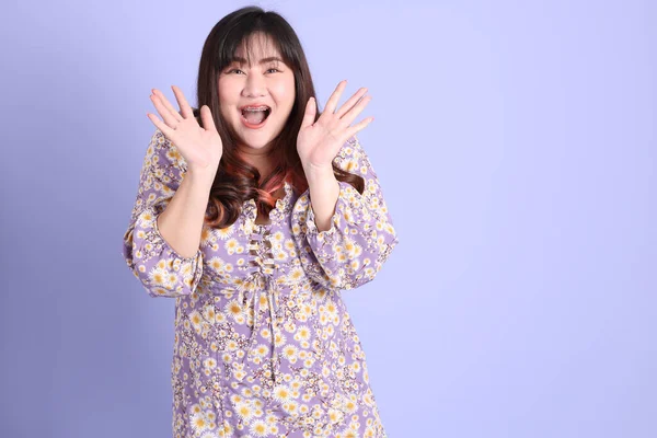 Mor arka planda sıradan kıyafetlerle duran tombul Asyalı kadın..