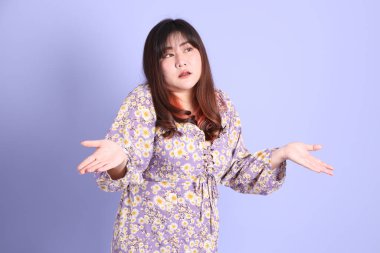 Mor arka planda sıradan kıyafetlerle duran tombul Asyalı kadın..