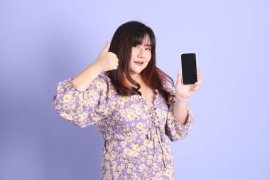 Mor arka planda sıradan kıyafetlerle duran tombul Asyalı kadın..