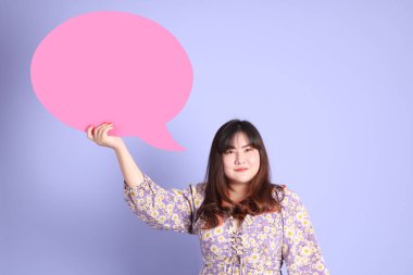 Mor arka planda sıradan kıyafetlerle duran tombul Asyalı kadın..