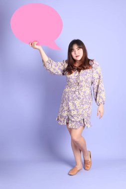 Mor arka planda sıradan kıyafetlerle duran tombul Asyalı kadın..