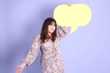 Mor arka planda sıradan kıyafetlerle duran tombul Asyalı kadın..