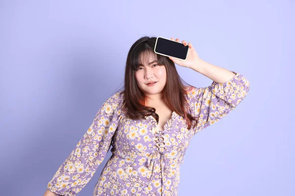 Mor arka planda sıradan kıyafetlerle duran tombul Asyalı kadın..