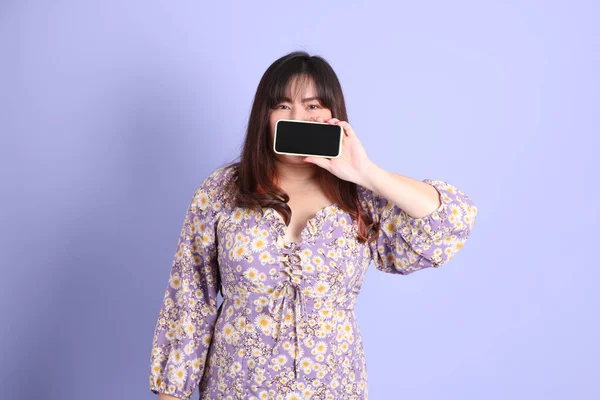 Mor arka planda sıradan kıyafetlerle duran tombul Asyalı kadın..