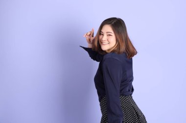 Mor arka planda sıradan kıyafetlerle duran tombul Asyalı kadın..