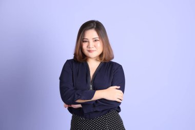 Mor arka planda sıradan kıyafetlerle duran tombul Asyalı kadın..