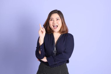 Mor arka planda sıradan kıyafetlerle duran tombul Asyalı kadın..